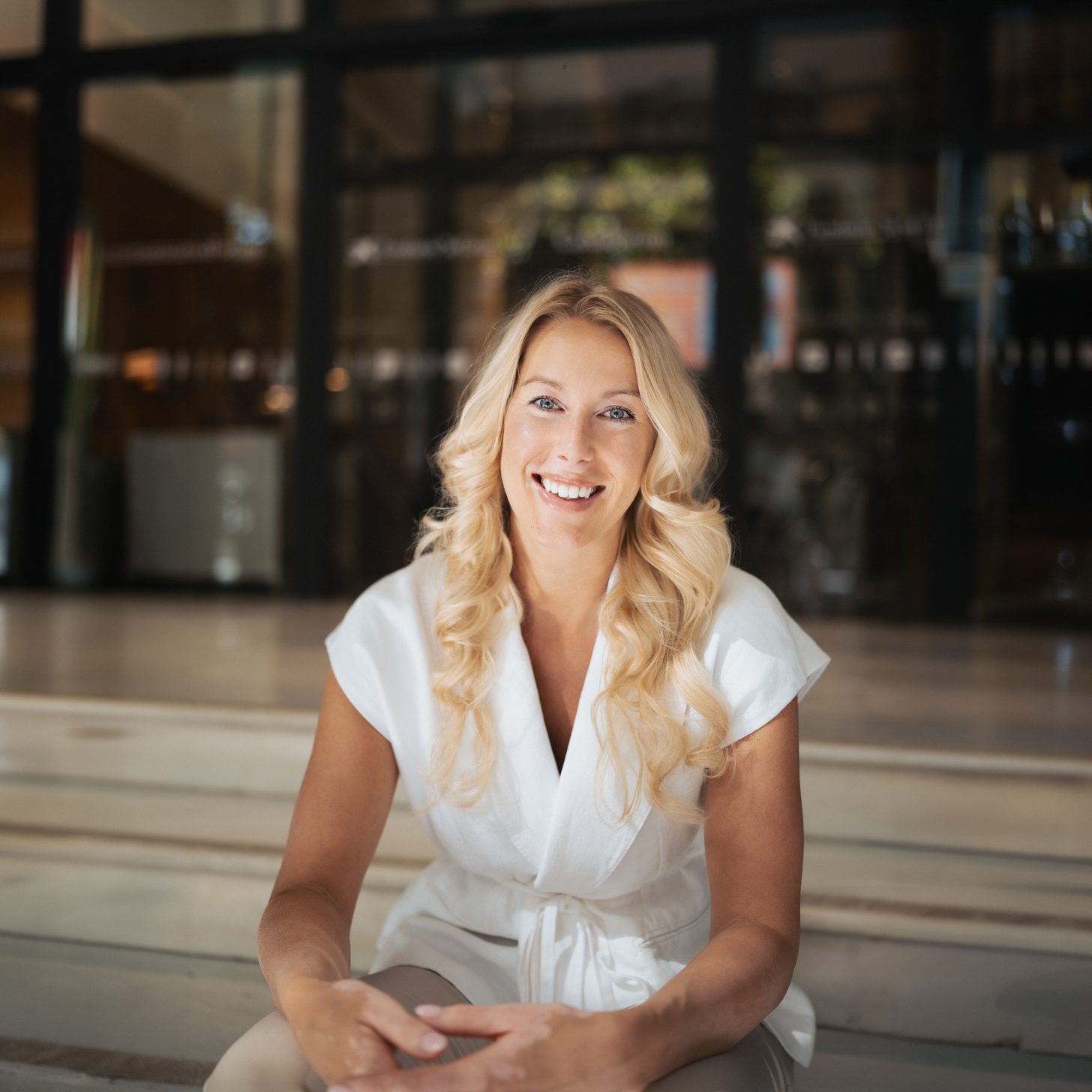 Alena Marquardt, Gründerin von Consult White, lächelnd auf hellen Stufen sitzend