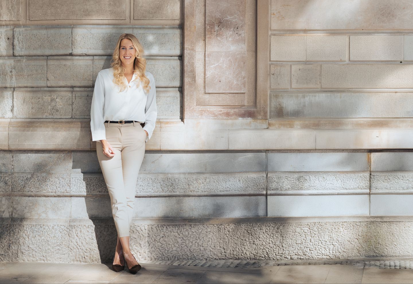 Alena, founder of Consult White, in front of a light natural stone wall